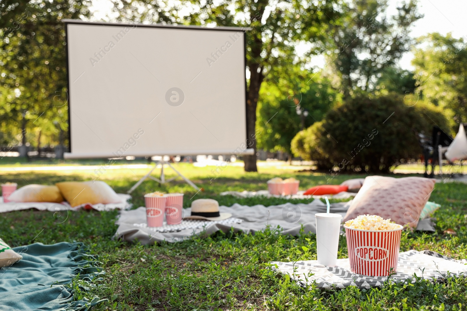 Photo of Popcorn and drink on green grass in open air cinema. Space for text