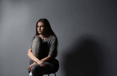 Depressed young woman on gray background