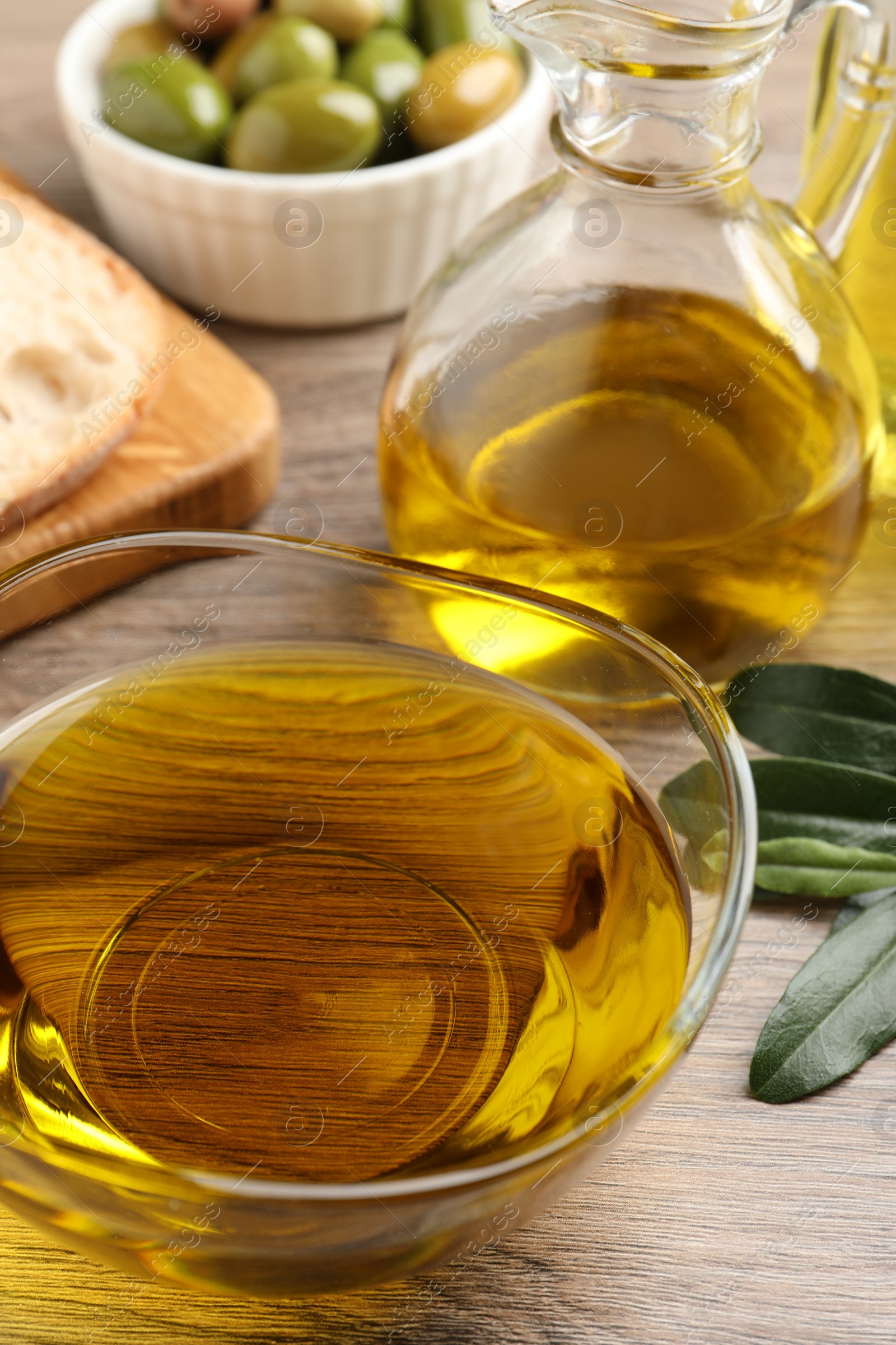 Photo of Fresh oil, ripe olives and green leaves on wooden table