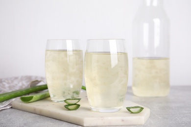 Photo of Fresh aloe drink in glasses on light grey table