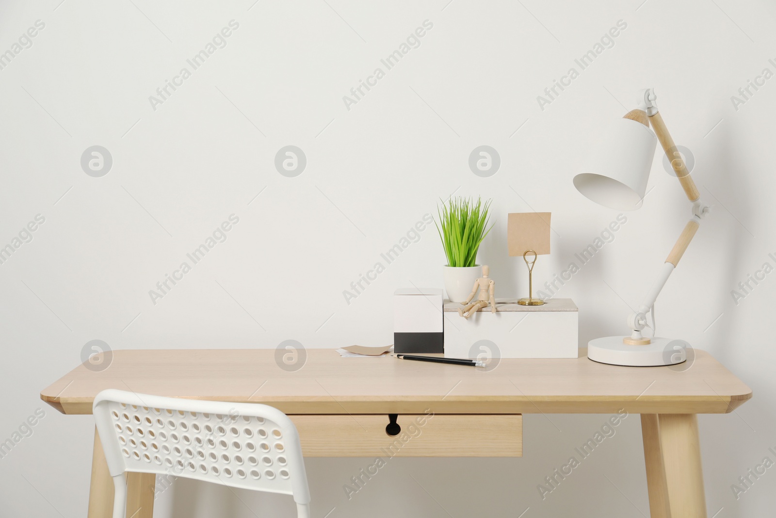 Photo of Comfortable workplace with wooden desk near white wall