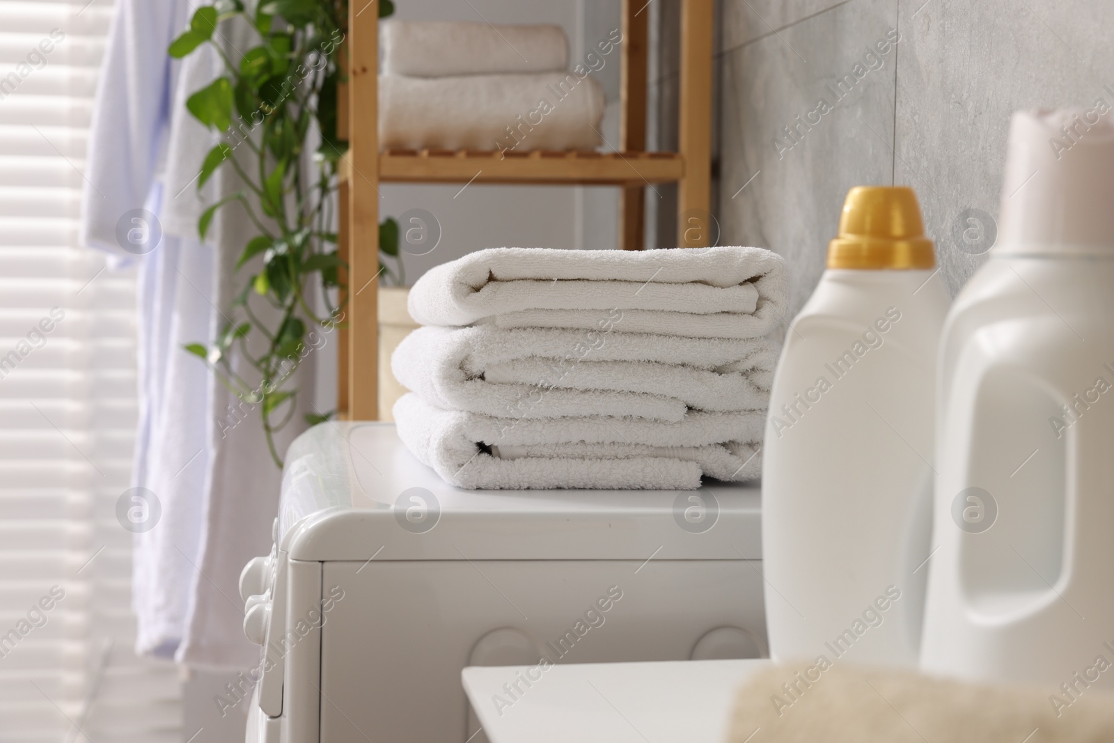 Photo of Soft towels, detergents and washing machine indoors, closeup