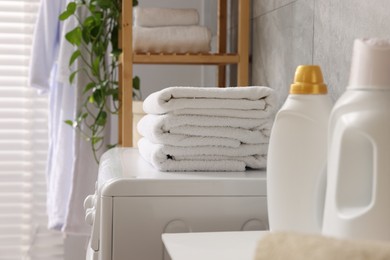 Photo of Soft towels, detergents and washing machine indoors, closeup