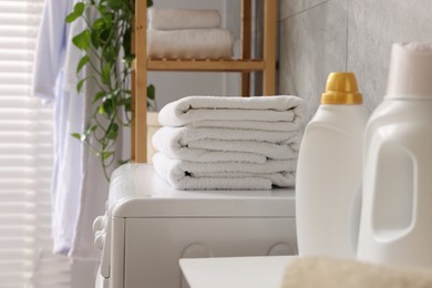 Soft towels, detergents and washing machine indoors, closeup