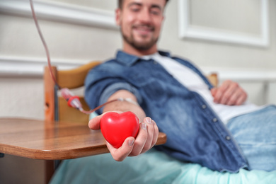 Photo of Young man making blood donation in hospital, focus on hand