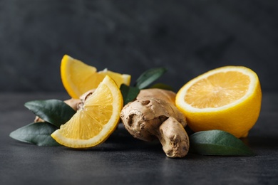 Photo of Fresh lemon and ginger on grey table, closeup