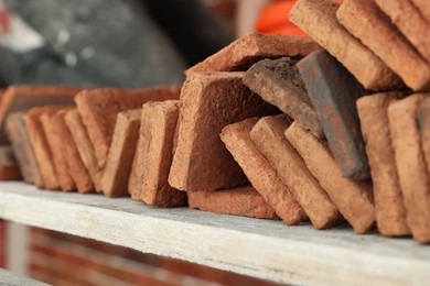 Photo of Many decorative bricks on scaffolding, closeup. Tiles installation process