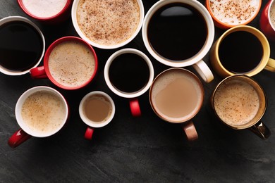 Many cups of different coffees on slate table, flat lay