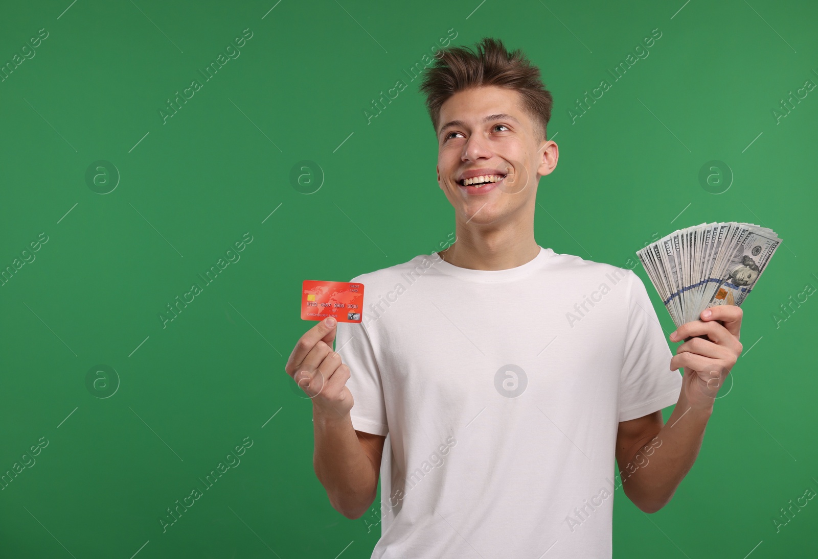 Photo of Happy man with credit card and dollar banknotes on green background. Space for text