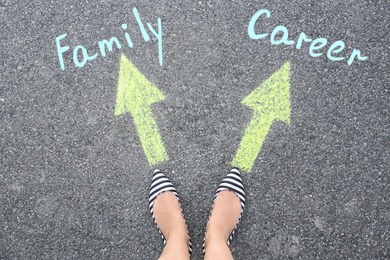 Image of Life choice. Woman on road near arrows with directions to family and career, top view