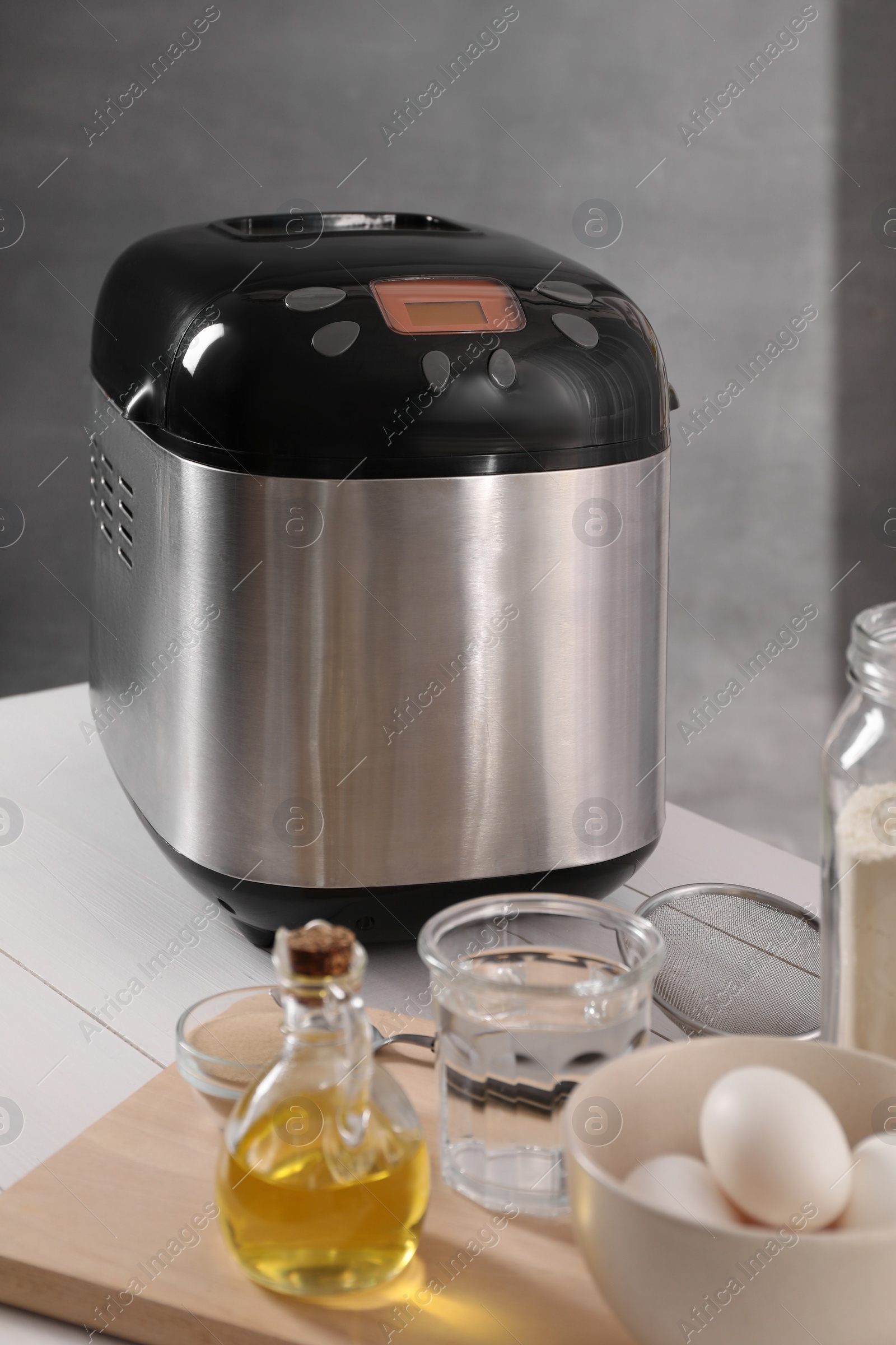 Photo of Breadmaker and different products on white wooden table indoors