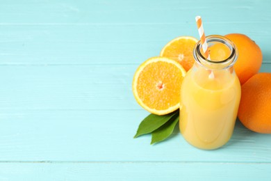 Photo of Bottle of orange juice and fresh fruits on light blue wooden table. Space for text