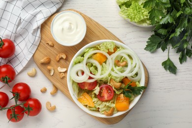 Bowl of delicious salad with Chinese cabbage and different ingredients on white wooden table, flat lay