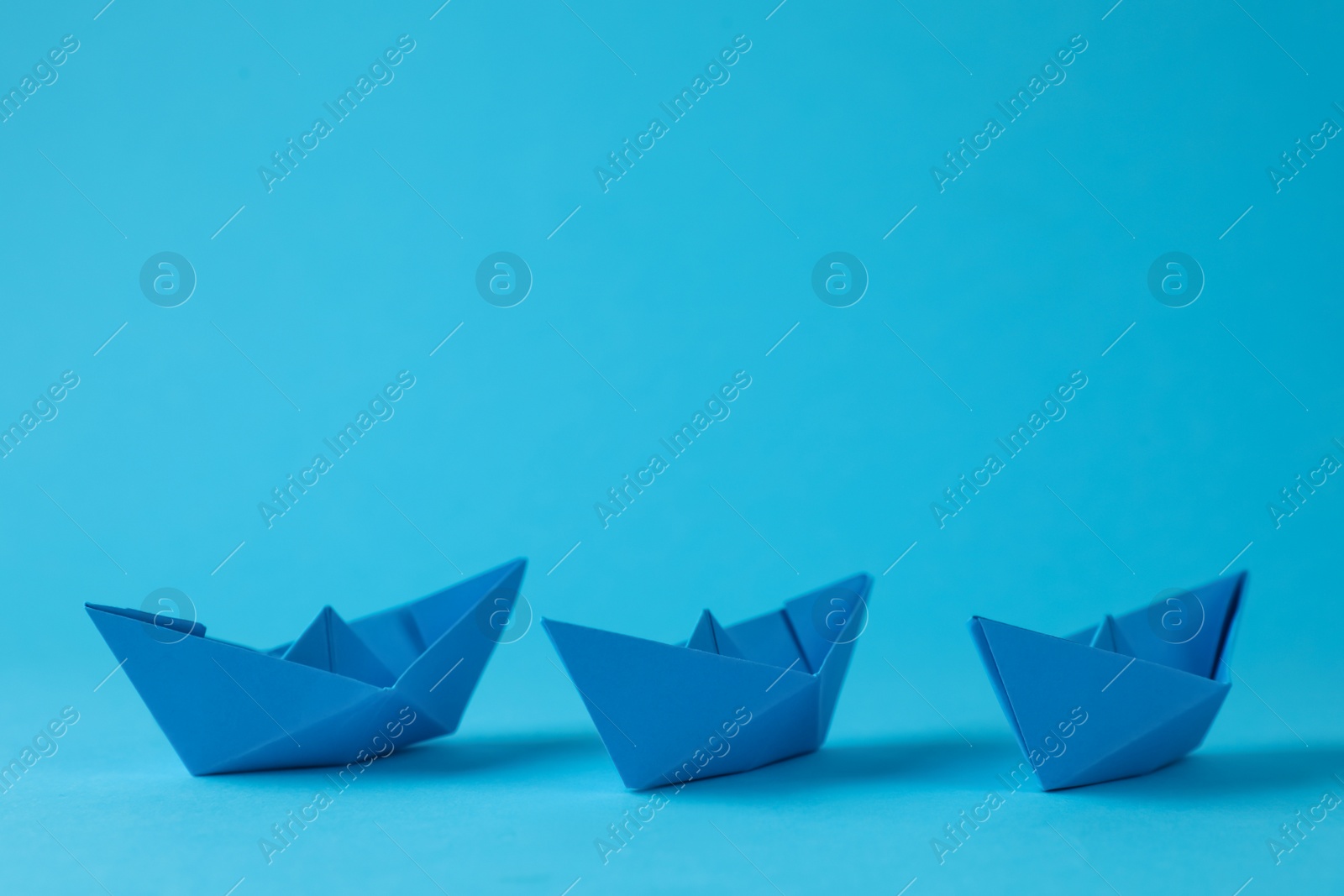 Photo of Handmade paper boats on light blue background. Origami art
