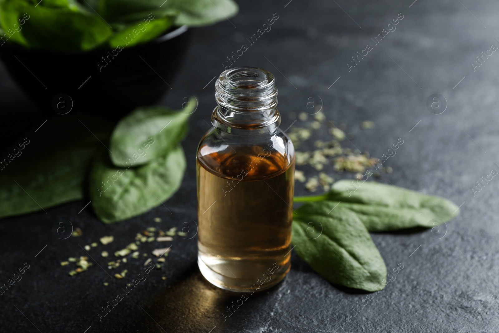 Photo of Essential oil of broadleaf plantain on black slate table, closeup