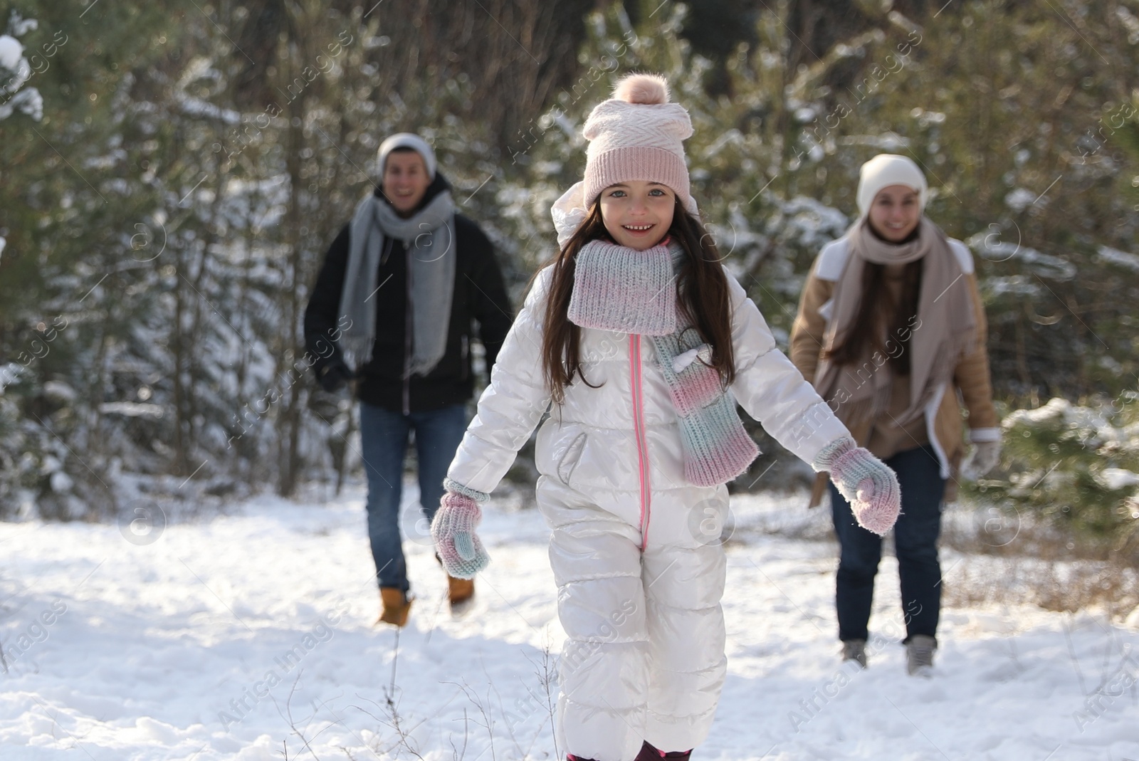 Photo of Cute little girl with her parents outdoors on winter day. Christmas vacation