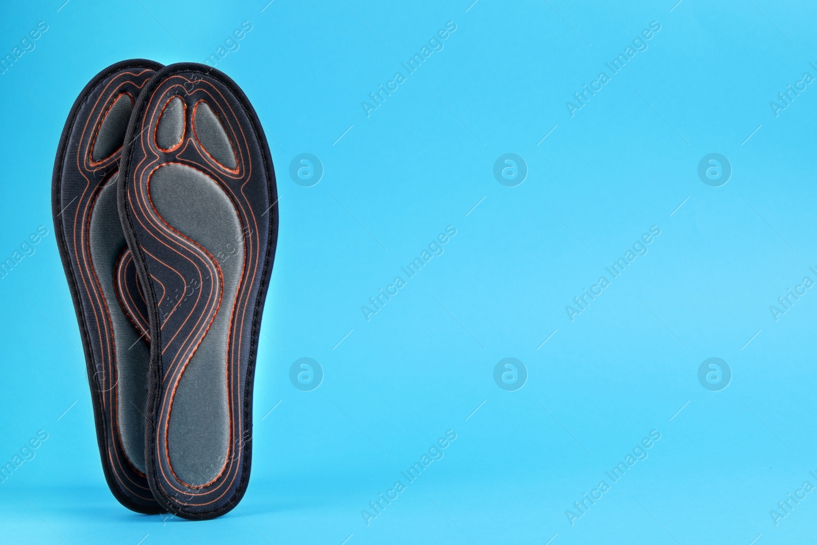 Photo of Pair of orthopedic insoles on light blue background, space for text