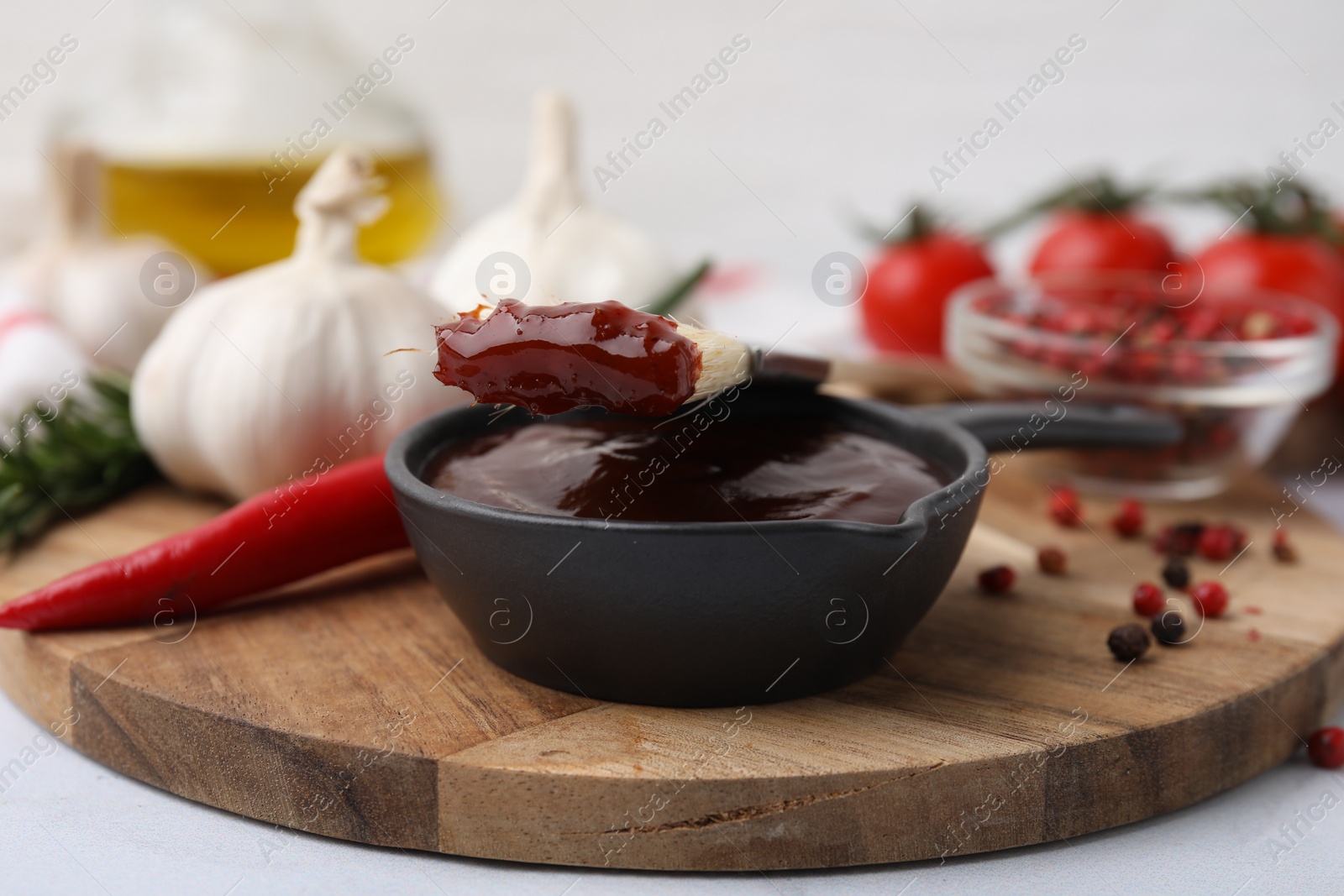 Photo of Marinade in gravy boat and basting brush on white table, closeup