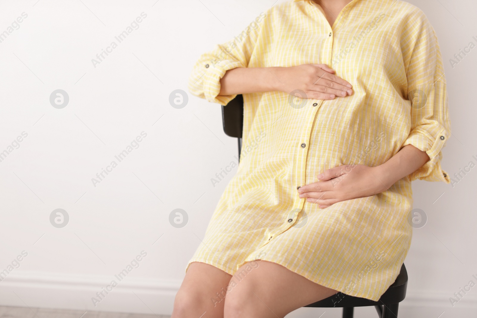 Photo of Beautiful pregnant woman sitting in light room, closeup