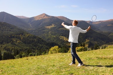 Man playing badminton in mountains on sunny day. Space for text