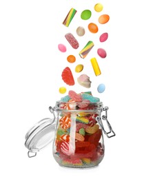 Different delicious candies falling into glass jar on white background 