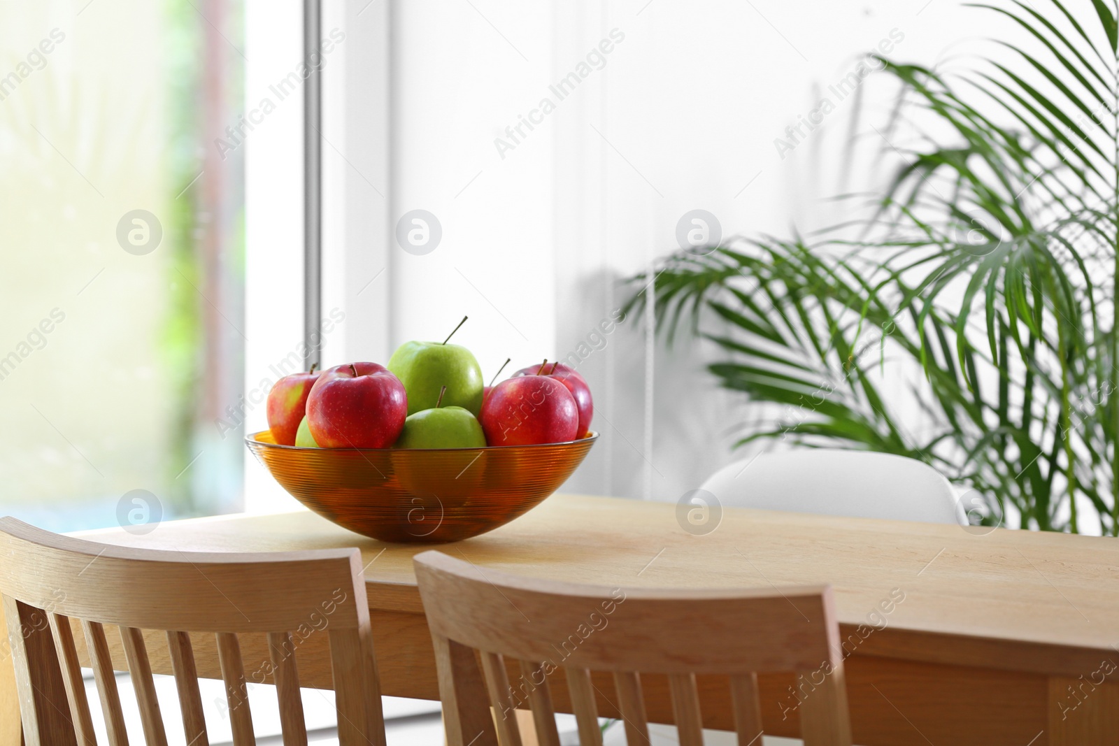 Photo of Bowl of fresh apples on table indoors. Space for text