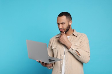 Photo of Thoughtful young man with laptop on light blue background