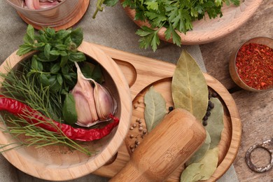 Mortar with pestle and different ingredients on wooden table, flat lay