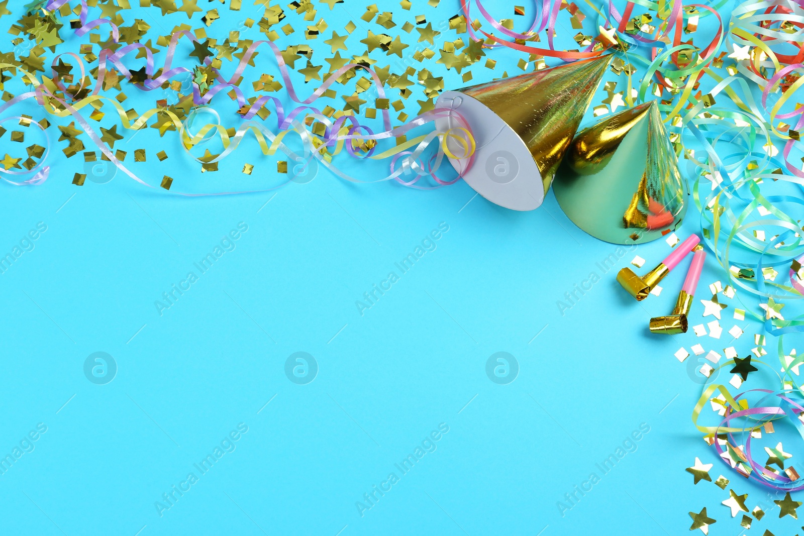 Photo of Colorful serpentine streamers, party horns, hats and confetti on light blue background, above view. Space for text