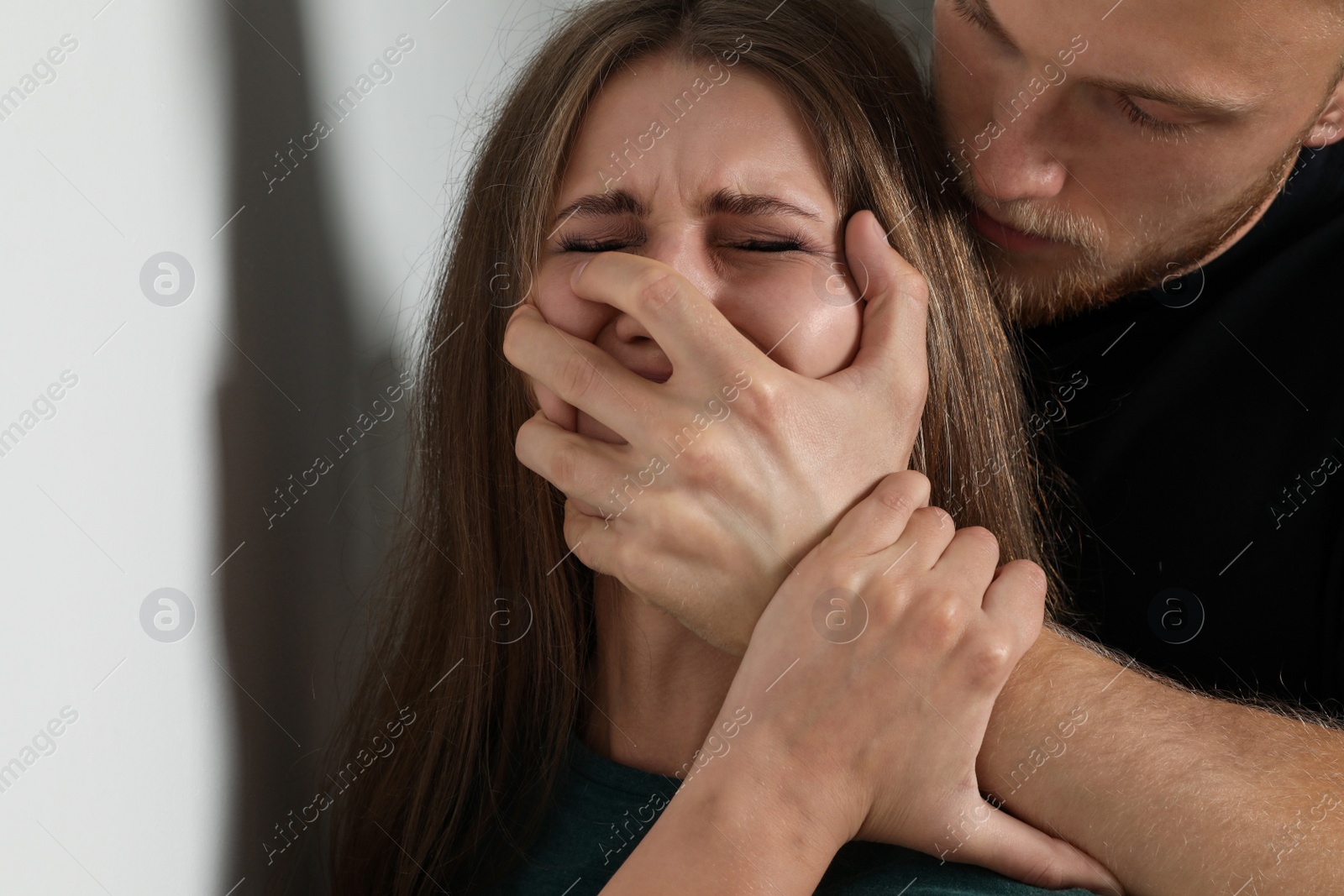 Photo of Man abusing young woman on light background. Stop sexual assault