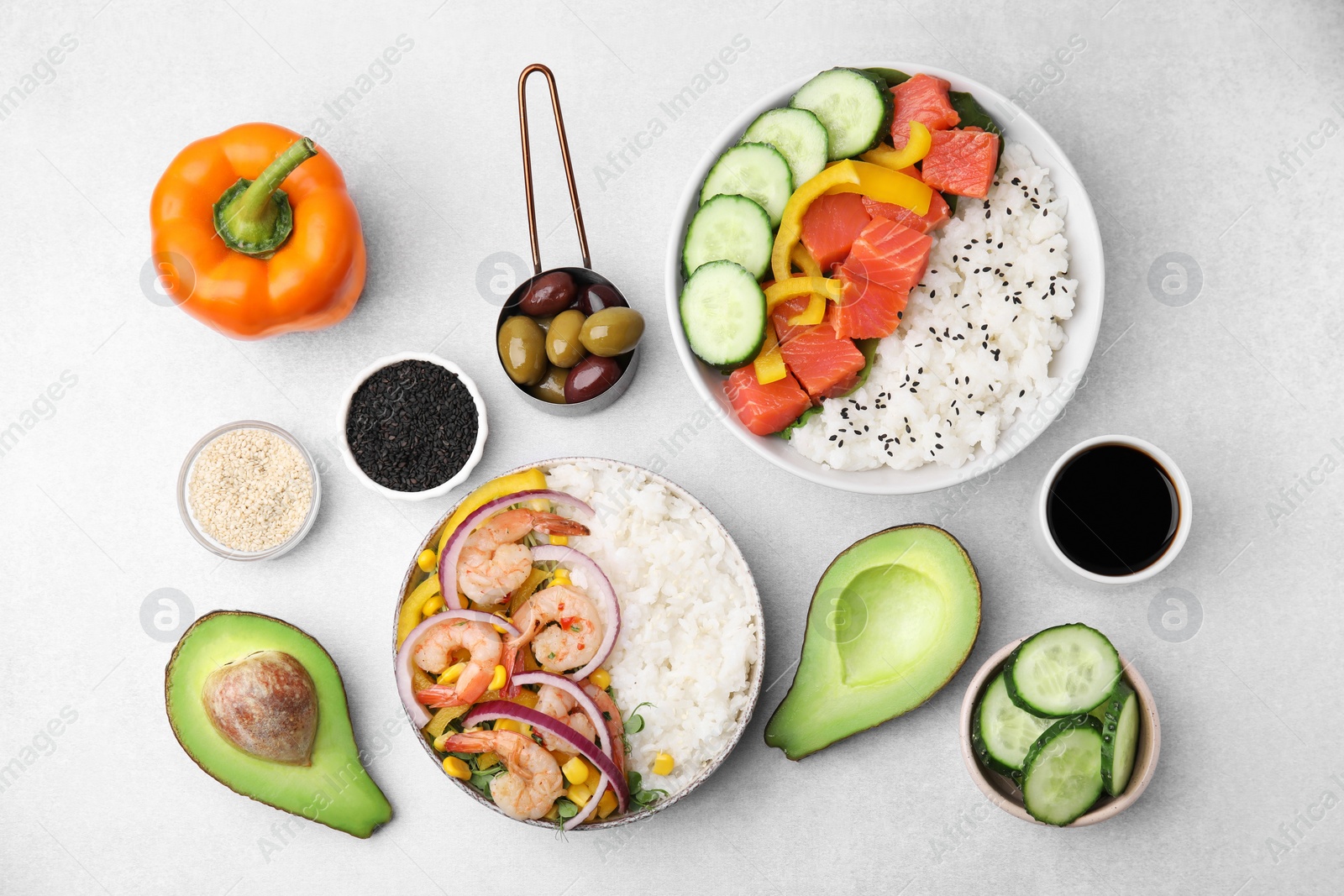 Photo of Poke bowls and ingredients on white table, flat lay