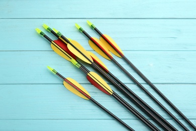 Photo of Plastic arrows on turquoise wooden table, flat lay. Archery sports equipment
