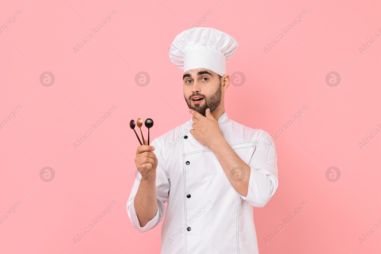 Photo of Professional chef holding kitchen utensils on pink background