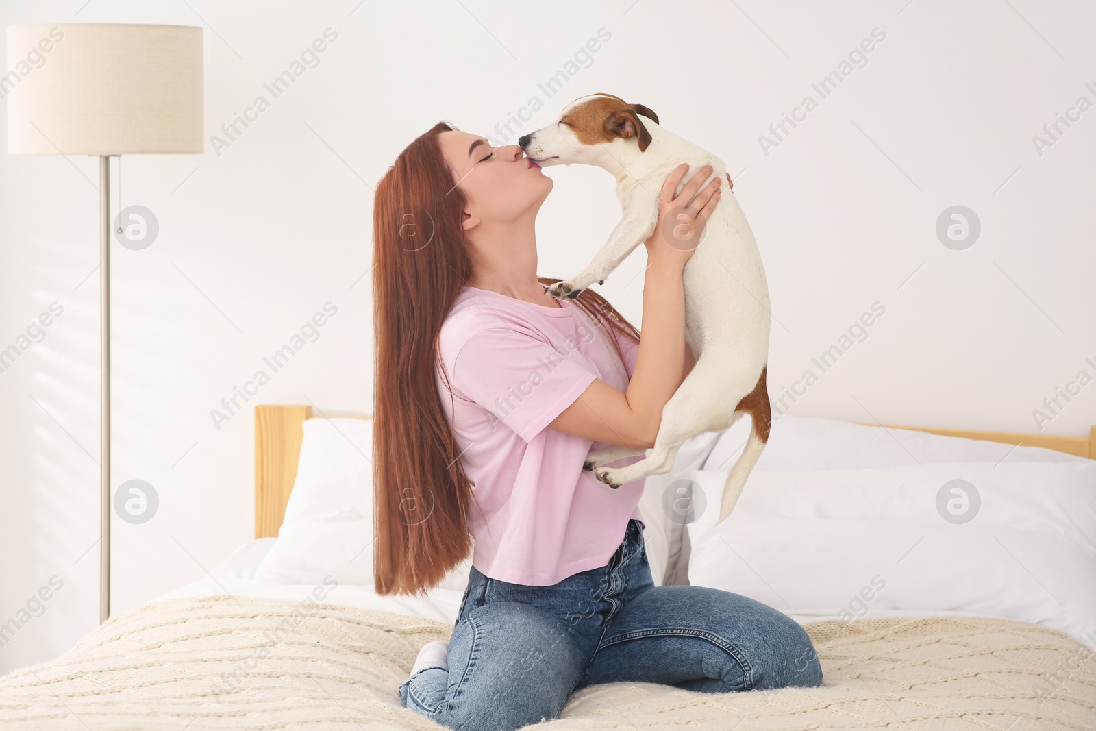 Photo of Woman kissing cute Jack Russell Terrier dog in bedroom