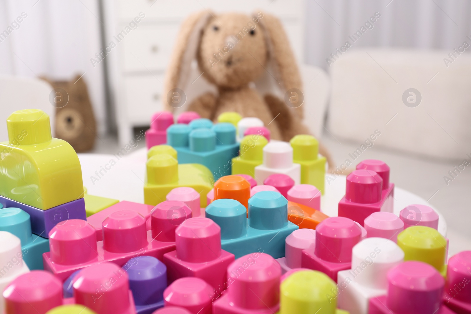Photo of Many colorful building blocks on table in room, closeup