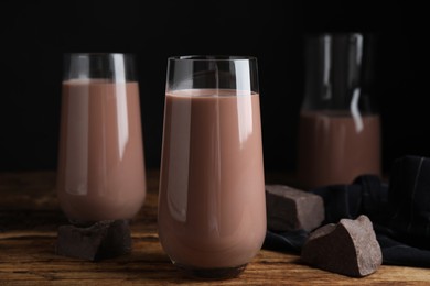 Delicious chocolate milk in glasses on wooden table