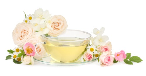 Aromatic herbal tea in glass cup and flowers isolated on white