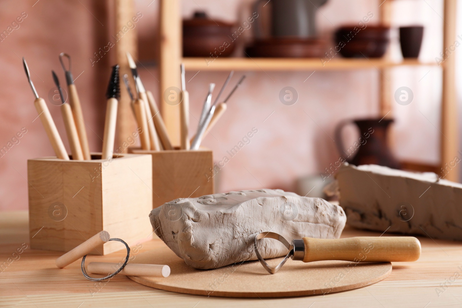 Photo of Clay and set of modeling tools on wooden table in workshop