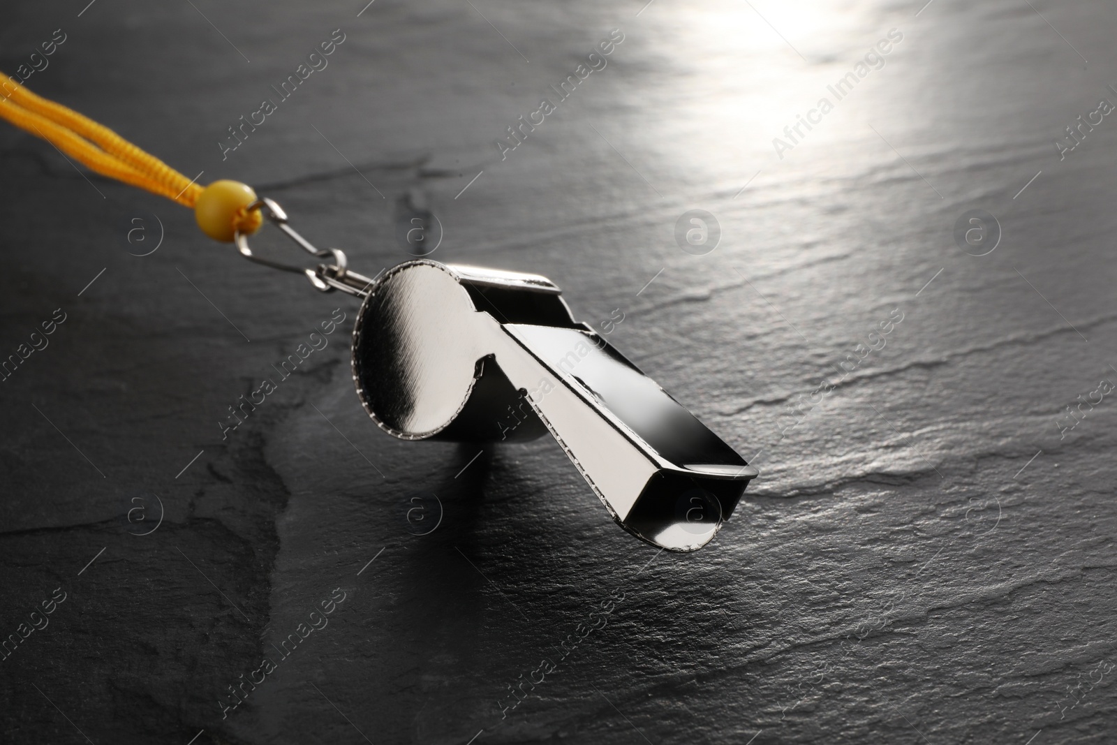 Photo of Referee equipment. Metal whistle on black textured background, closeup and space for text