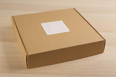 Photo of Closed cardboard box on wooden table, closeup