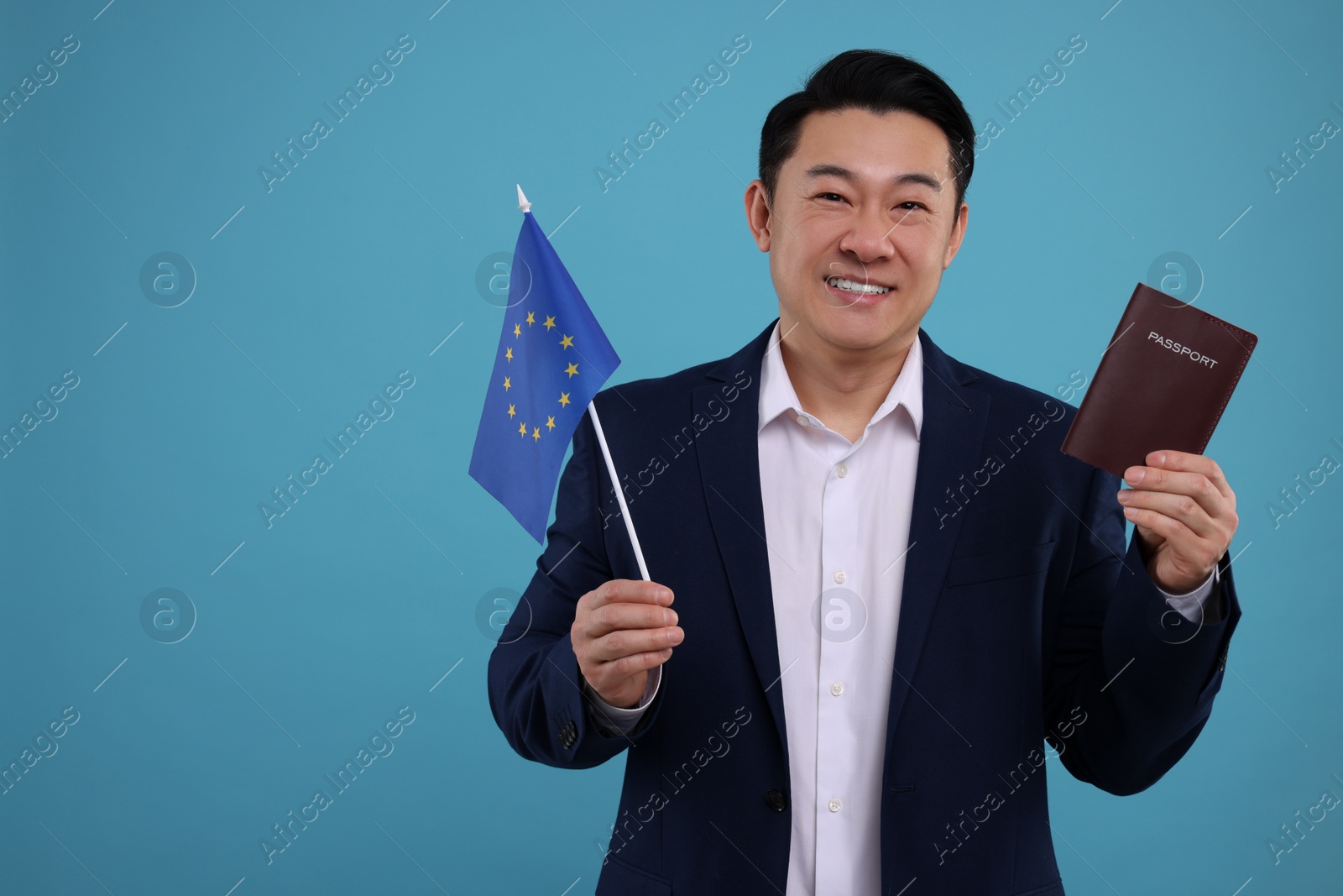 Photo of Immigration. Happy man with passport and flag of European Union on light blue background, space for text