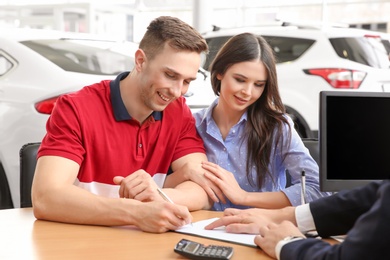 Young couple buying new car at dealership