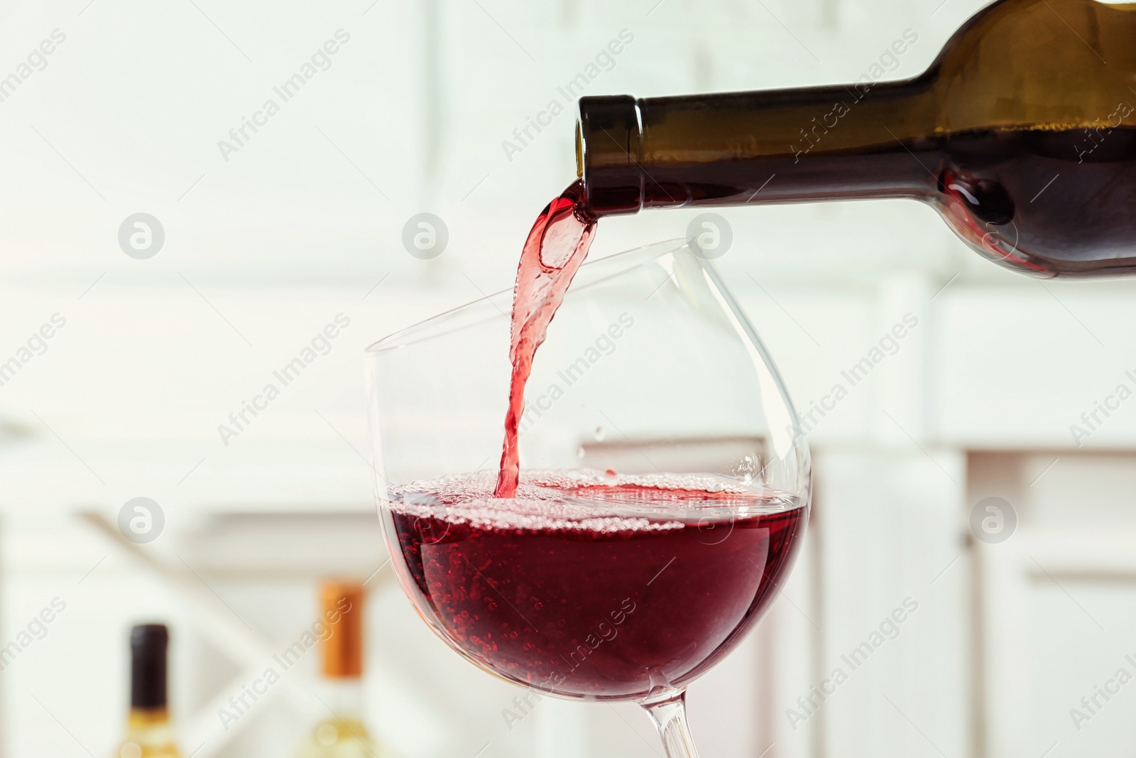 Photo of Pouring delicious red wine into glass on light background