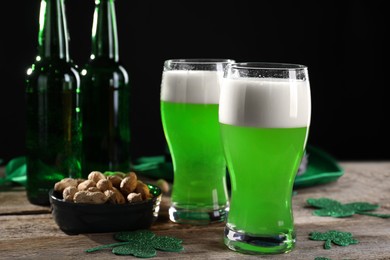 Photo of St. Patrick's day party. Green beer, nuts and decorative clover leaves on wooden table