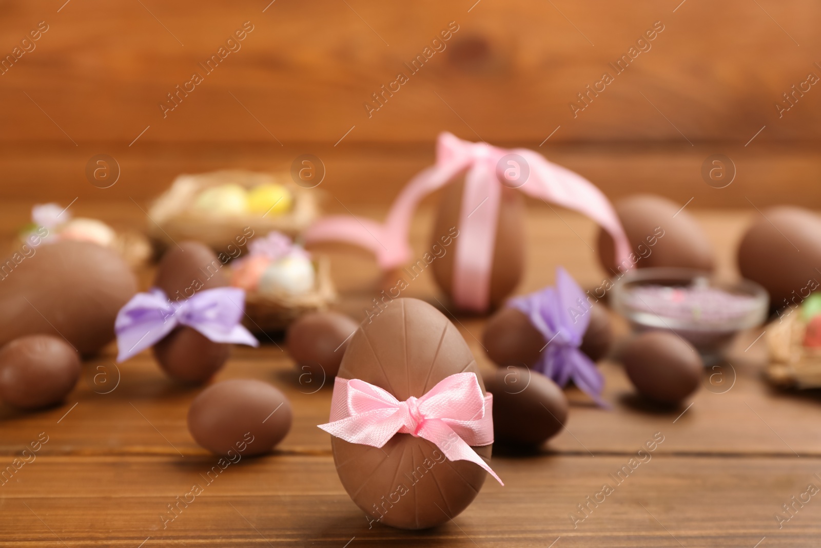 Photo of Sweet chocolate eggs on wooden table. Space for text