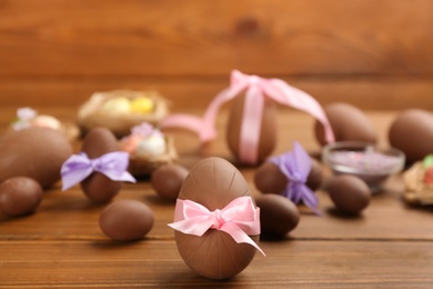 Photo of Sweet chocolate eggs on wooden table. Space for text