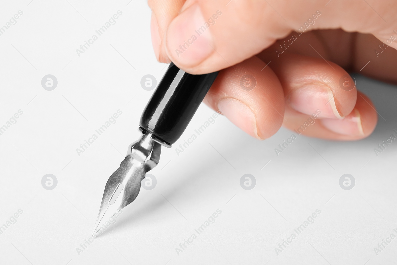 Photo of Woman with fountain pen above white paper, closeup