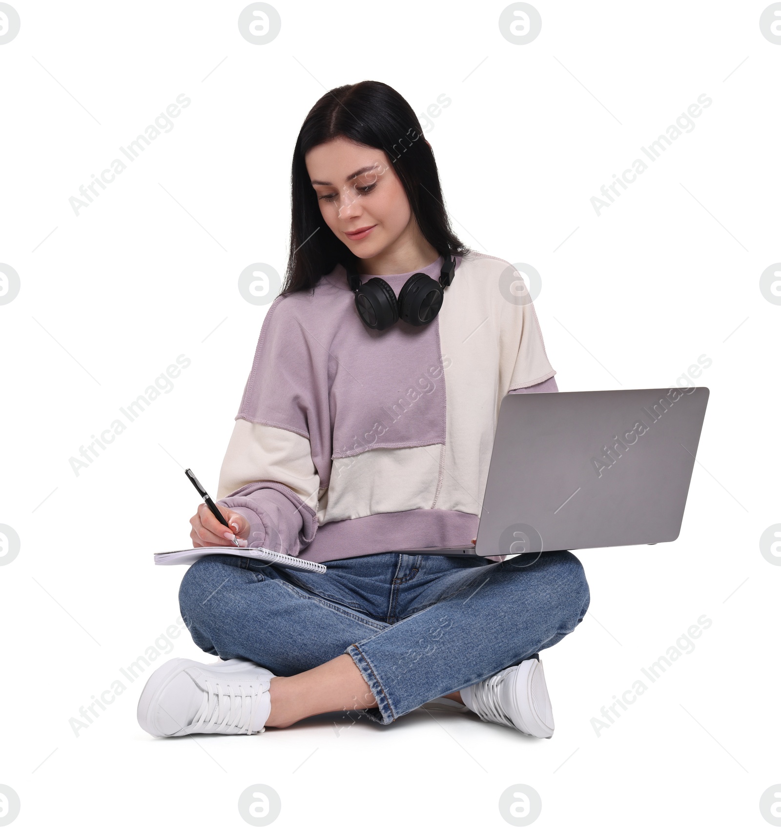 Photo of Student with laptop writing in notebook on white background