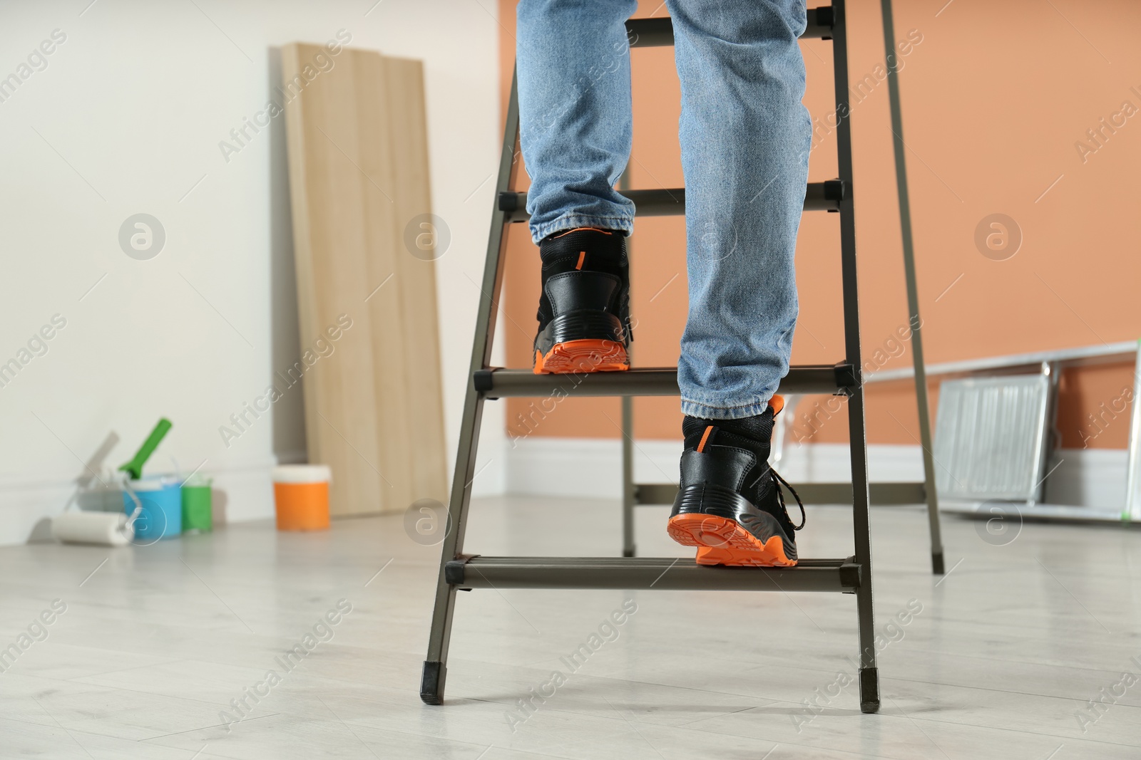 Photo of Person climbing ladder indoors, closeup on feet. Space for text