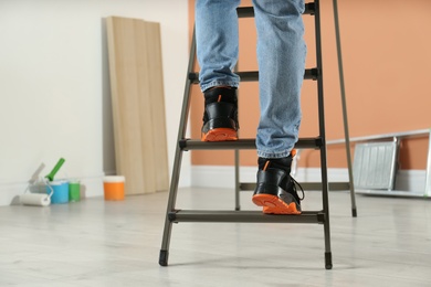 Photo of Person climbing ladder indoors, closeup on feet. Space for text